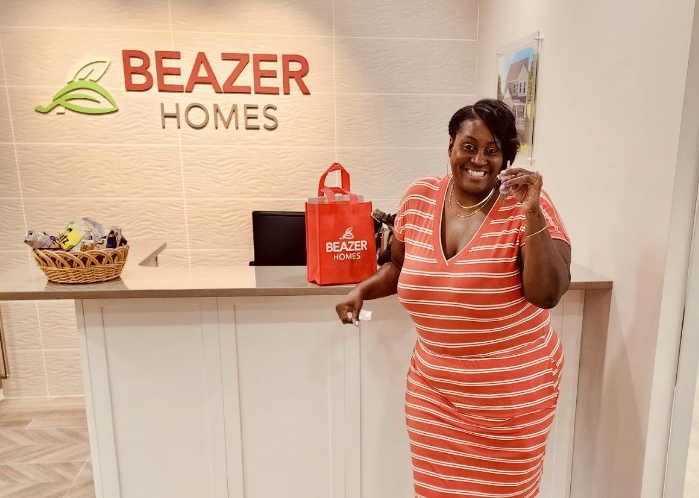 Woman standing in Beazer office holding key to her new home