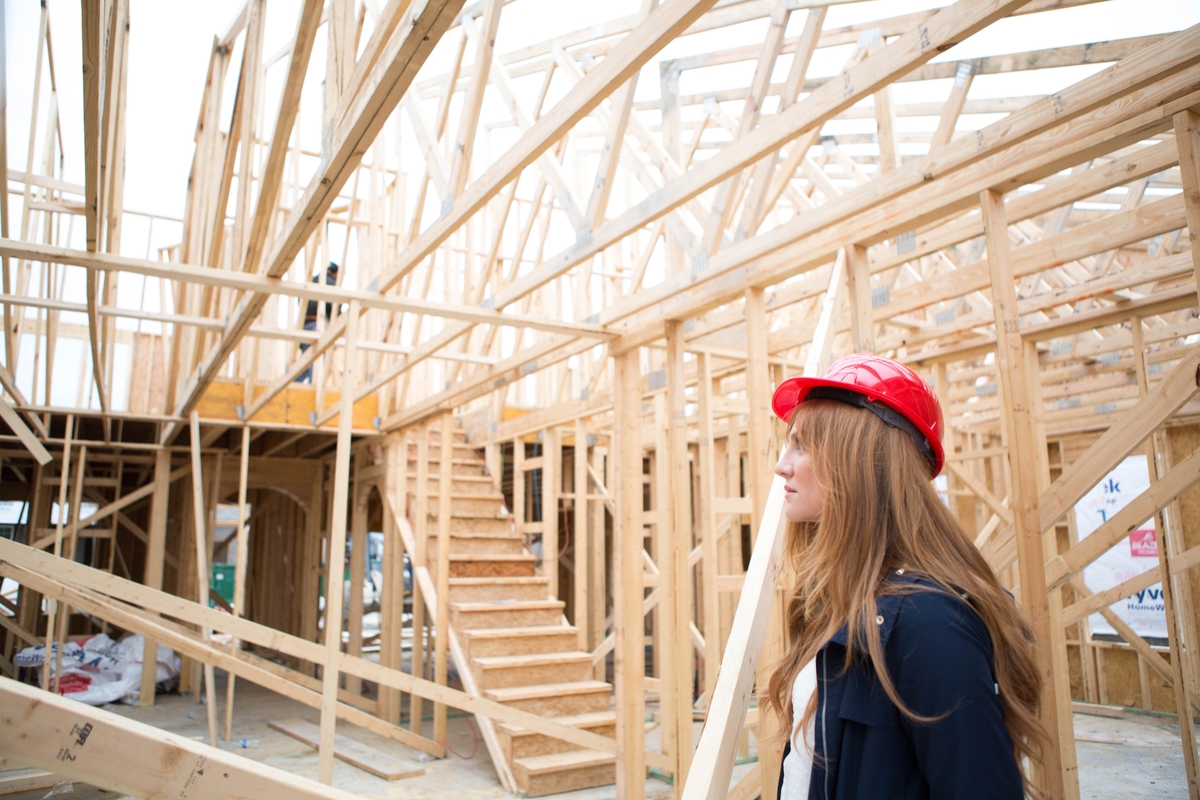 woman in a hard hat standing in a home that is under construction